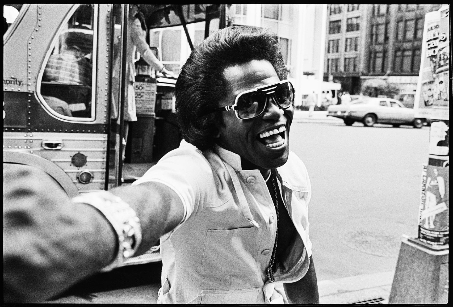 Laughing man in sunglasses reaching toward camera