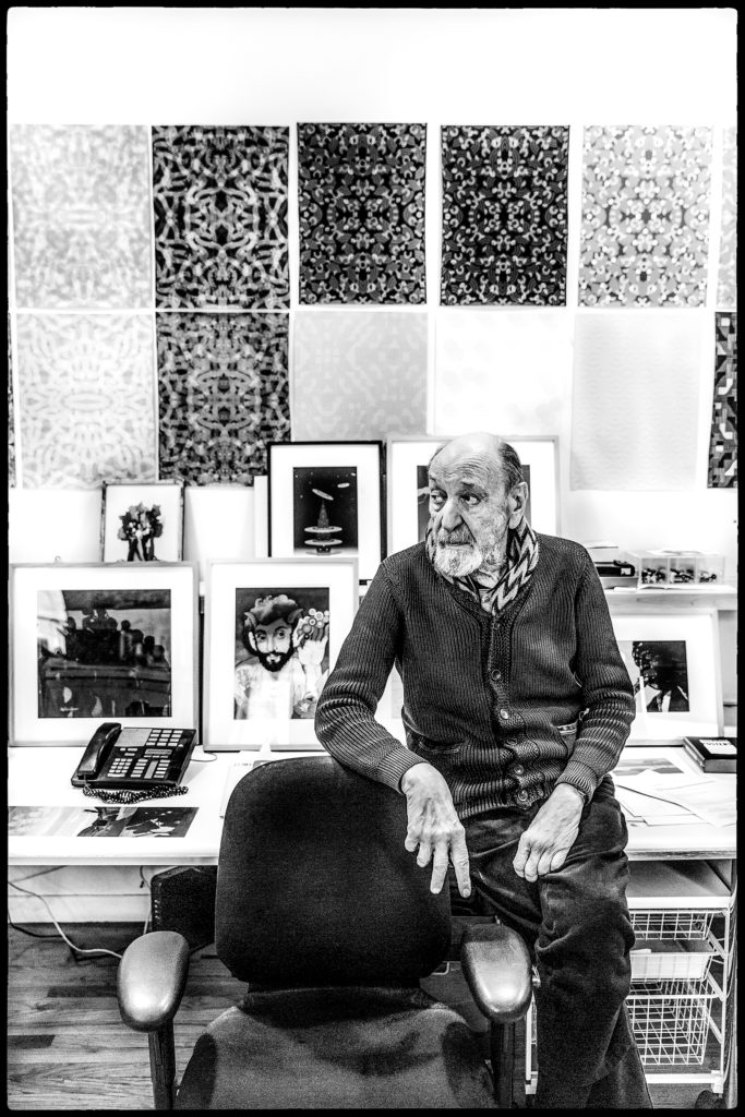 Older man seated in art-filled studio